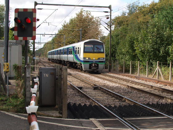 An electric commuter train approaching a level crossing